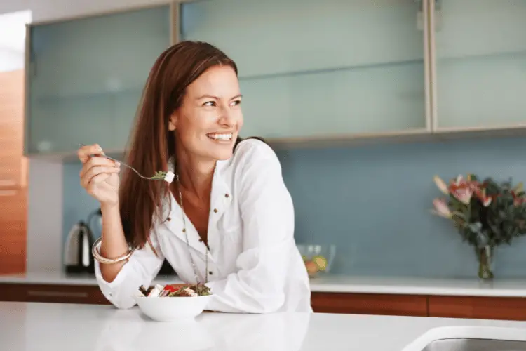 Woman eating a salad at a kitchen island