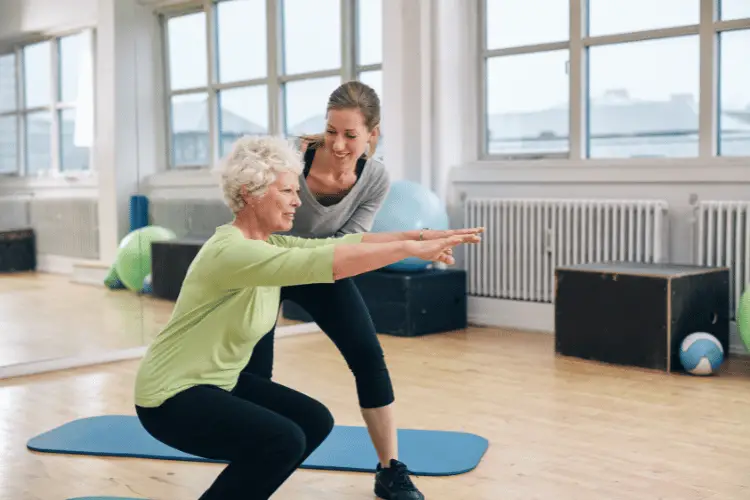 a personal trainer helping an old woman 