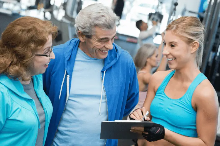 a gym employee explaining the gym membership to a senior couple 