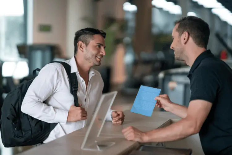 a man talking to the gym receptionist 