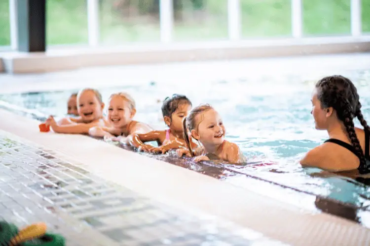 A group of kids attending a swimming class listening to their teacher